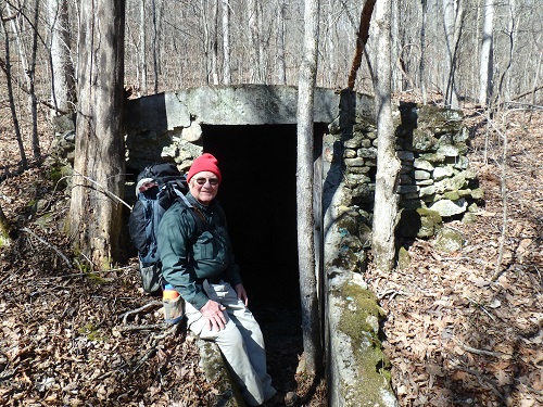 hiker standing beside discovered root cellar
